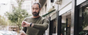 Man holding smart phone checking time on wristwatch