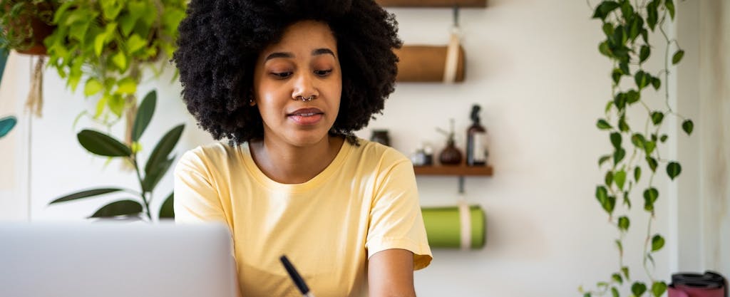 Latin woman with Afro hair using laptop at home