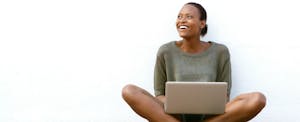 Une femme souriante travaille sur son ordinateur portable à l'extérieur