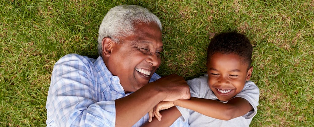 Un grand-père qui rit joue avec son petit-fils sur la pelouse