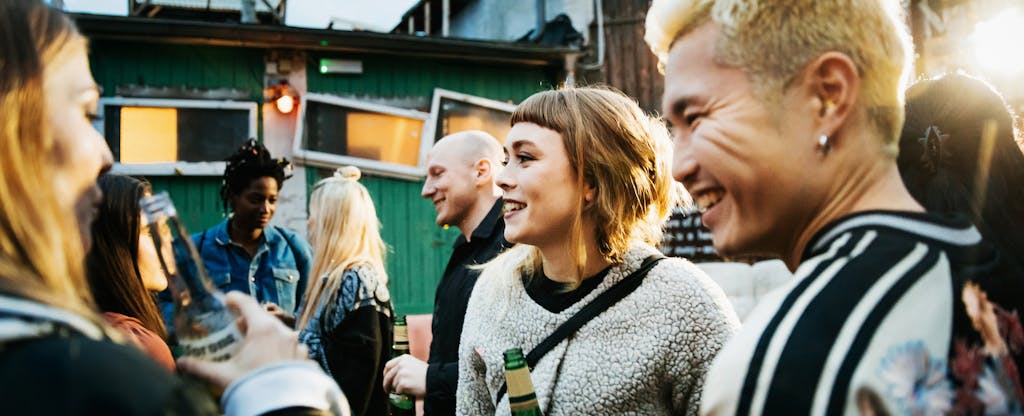 Young group of clubgoers drinking and catching up together while dancing at a trendy open air nightclub.