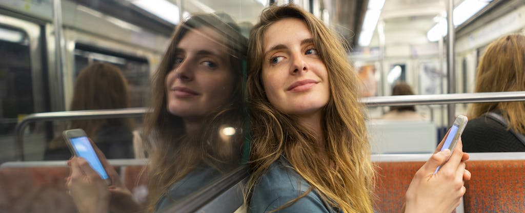 Portrait of smiling young woman and her mirror image in underground train. She wonders what a line of credit is.