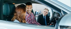 Experienced salesman selling a car to a young couple
