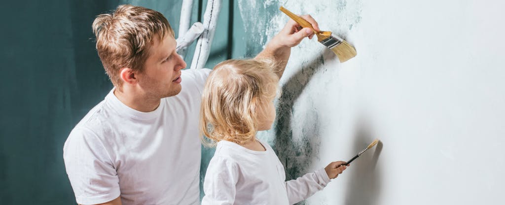 Father and young daughter painting a wall, while the father teaches her about credit card utilization and how it affects your credit score