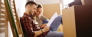 Couple reading a letter while sitting on the floor with moving boxes