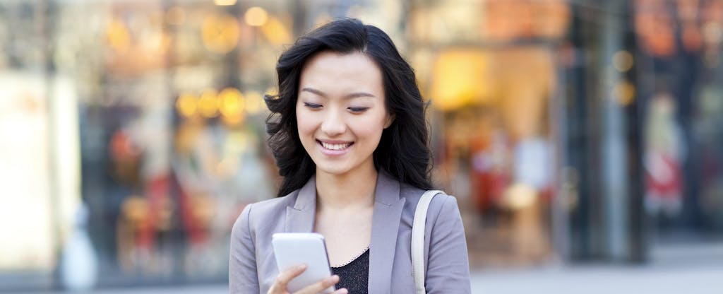 Happy young woman with shopping bags checking smart phone