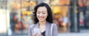 Happy young woman with shopping bags checking smart phone