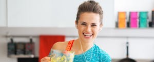 Portrait of happy fitness woman with pumpkin smoothie in kitchen