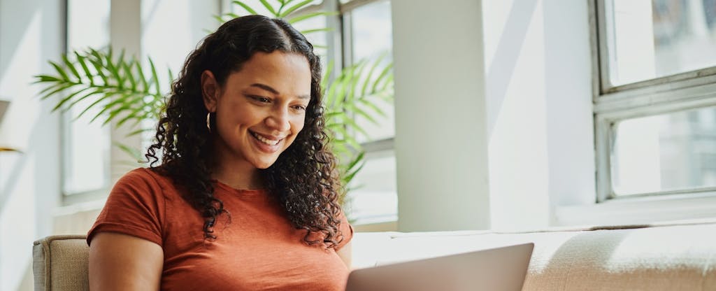 Shot of a young black woman sitting with her laptop computer, smiling with copy space. Stock photo