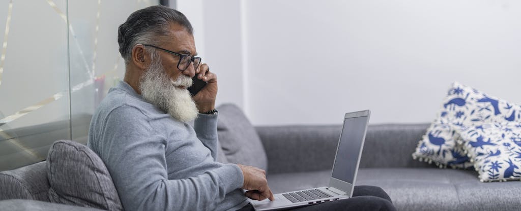 Latino man is inside the office where he works with his laptop in his hands with which he does his pending work while standing at the door of his office