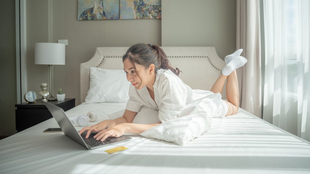 Woman working from home in her bed with laptop